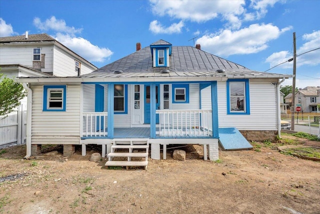 rear view of house featuring a porch, fence, a standing seam roof, and metal roof