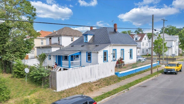 rear view of property featuring fence, metal roof, a chimney, and a standing seam roof