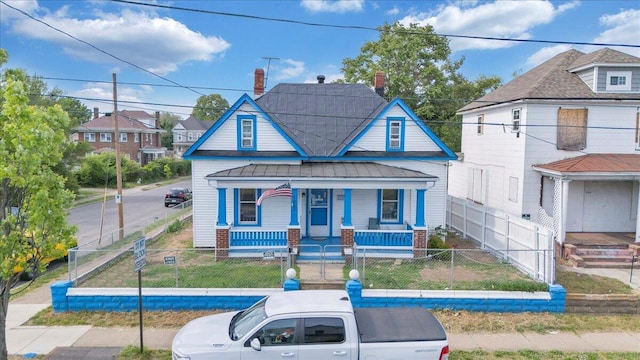 bungalow with a porch, brick siding, a residential view, and a fenced front yard