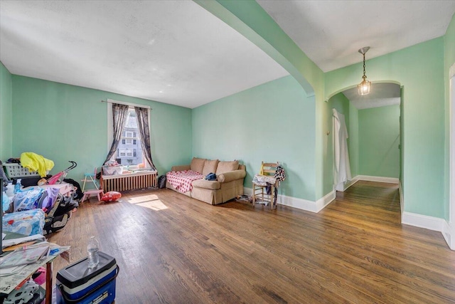 living room featuring arched walkways, baseboards, and wood finished floors