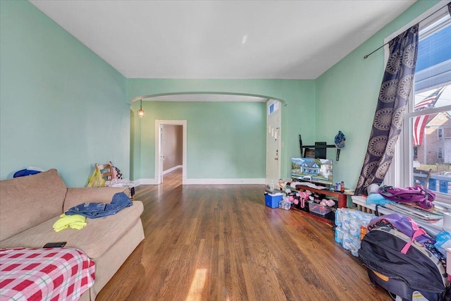 living room with baseboards, arched walkways, and wood finished floors