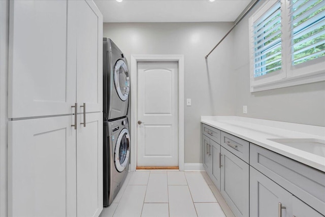 400 Heather Ln, Huddleston, VA 24104 - laundry area featuring stacked washer and clothes dryer, light tile patterned floors, cabinet space, and baseboards