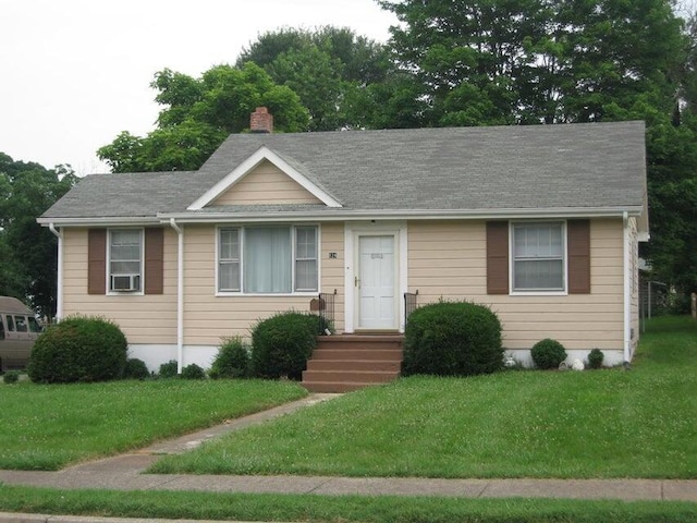 view of front of house featuring a shingled roof, a chimney, and a front lawn
