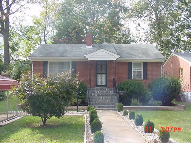 view of front of home with brick siding, a front lawn, and a chimney