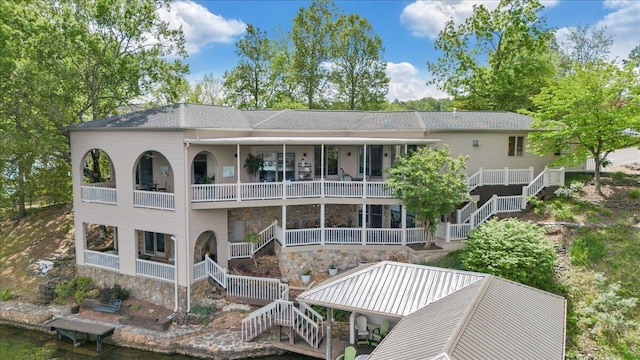 back of house with stairs and stone siding
