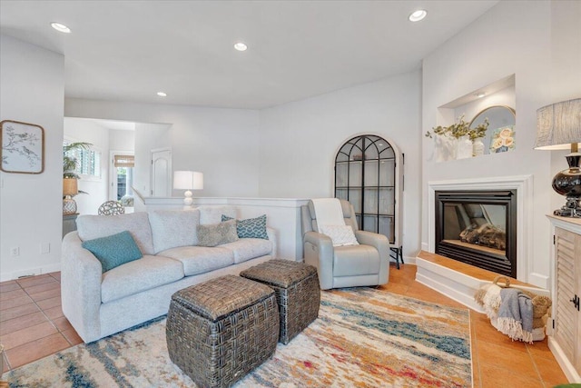 tiled living area with baseboards, a glass covered fireplace, and recessed lighting