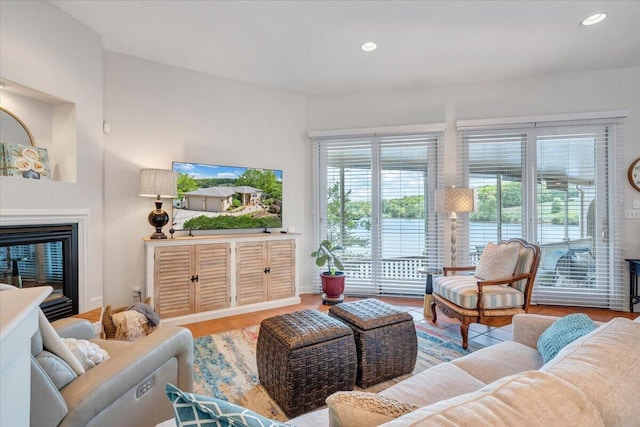 living area with a glass covered fireplace, recessed lighting, and wood finished floors