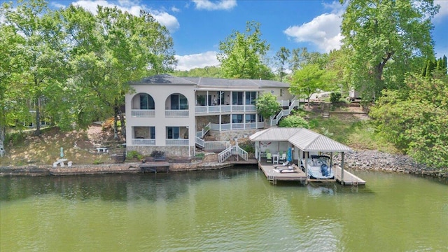 view of dock featuring boat lift, a balcony, a water view, and stairs