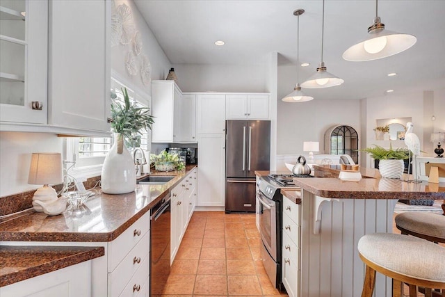 kitchen with a center island, a sink, stainless steel appliances, a kitchen breakfast bar, and white cabinets