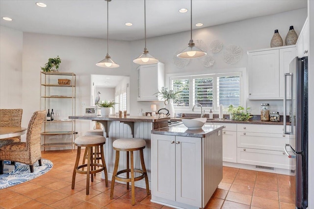 kitchen featuring freestanding refrigerator, dark countertops, white cabinetry, and recessed lighting