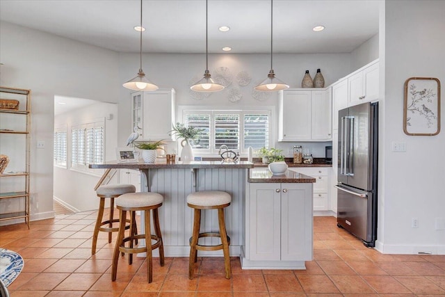 kitchen featuring white cabinets, plenty of natural light, a breakfast bar, and high end refrigerator