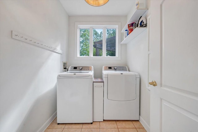 laundry area featuring baseboards, washing machine and dryer, laundry area, and light tile patterned flooring