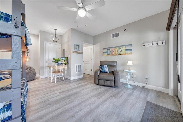 living area featuring visible vents, wood finished floors, baseboards, and ceiling fan