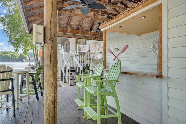 wooden terrace featuring ceiling fan, stairs, and a water view