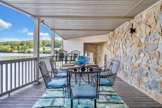 deck with a water view and outdoor dining area