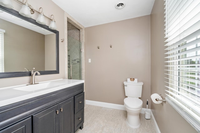 bathroom with toilet, vanity, visible vents, baseboards, and a tile shower