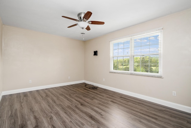 spare room featuring baseboards, ceiling fan, and dark wood-style floors