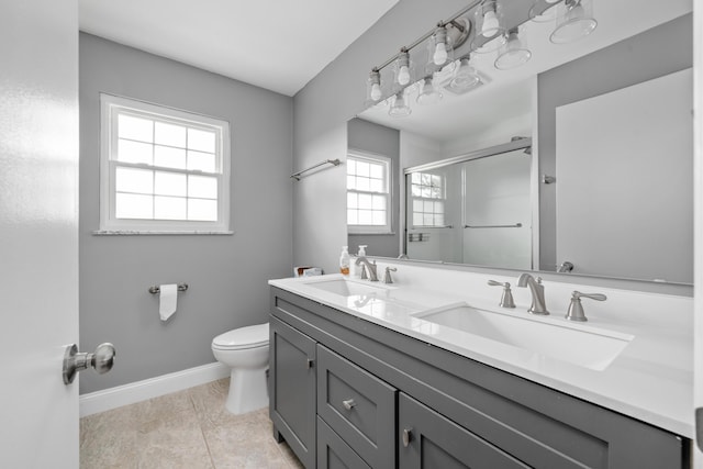 full bathroom featuring toilet, baseboards, a shower stall, and a sink