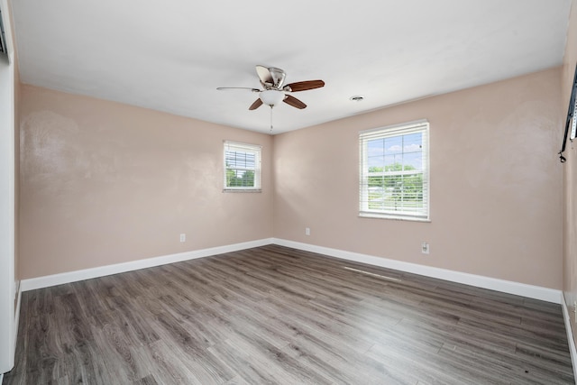 spare room featuring plenty of natural light, baseboards, a ceiling fan, and wood finished floors