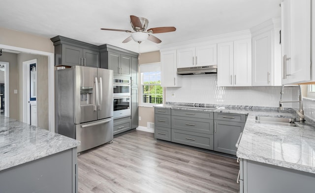 kitchen with under cabinet range hood, stainless steel appliances, gray cabinetry, and a sink