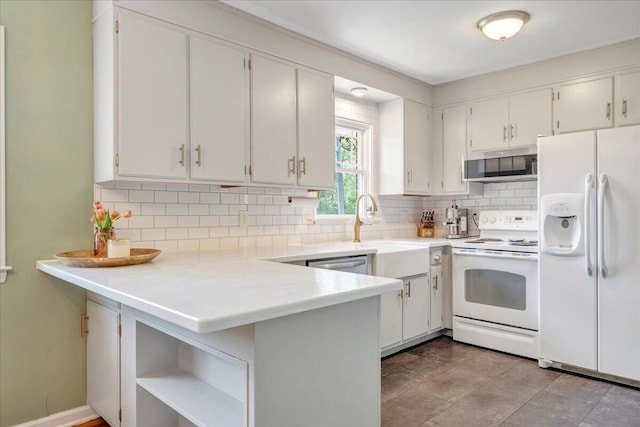 kitchen featuring a sink, white appliances, light countertops, a peninsula, and decorative backsplash