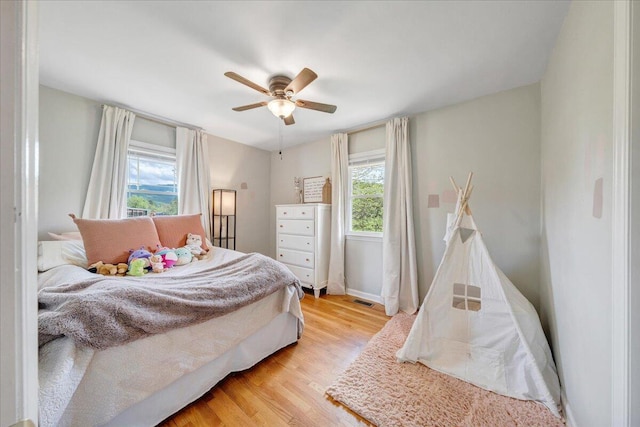 bedroom with ceiling fan, visible vents, baseboards, and light wood-style floors