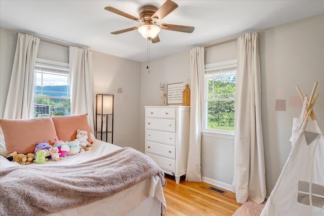 bedroom with baseboards, ceiling fan, light wood-type flooring, and visible vents