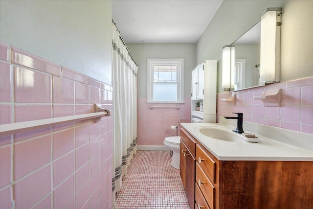 full bathroom featuring tile patterned flooring, vanity, toilet, tile walls, and a wainscoted wall