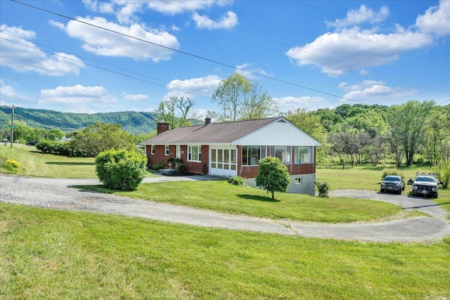 ranch-style home with a chimney, a front lawn, and brick siding