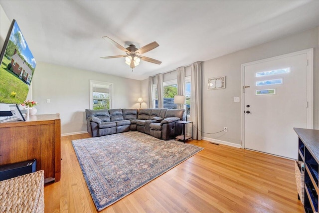 living area featuring baseboards, ceiling fan, visible vents, and light wood-style flooring