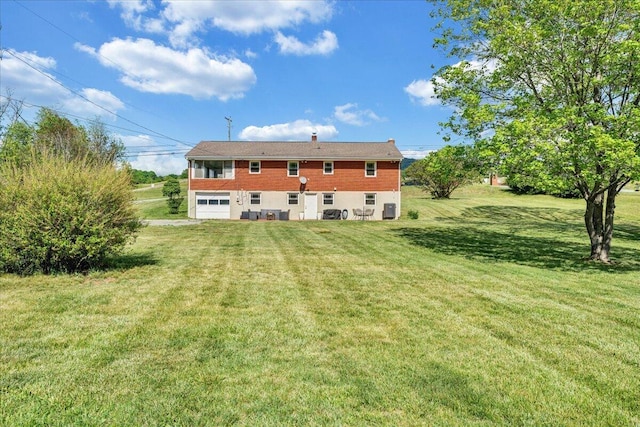 back of house featuring a garage and a yard