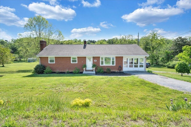 single story home featuring brick siding, a chimney, and a front lawn