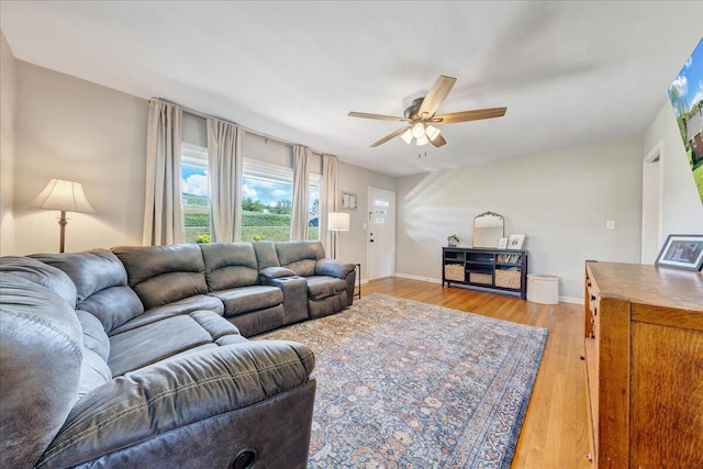 living room with a ceiling fan, baseboards, and light wood-style floors