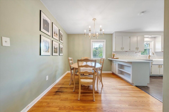 dining room with baseboards, light wood-style flooring, and a notable chandelier