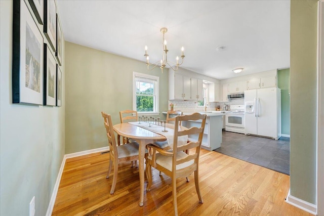 dining area with light wood-style floors, baseboards, and a chandelier