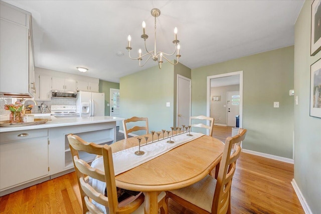 dining room featuring baseboards, light wood-style flooring, and a chandelier