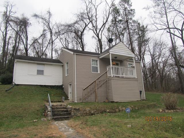 view of front of property featuring stairs and a front lawn