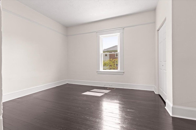 spare room featuring baseboards, visible vents, and dark wood-type flooring