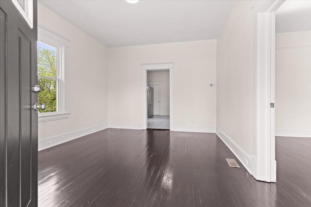 unfurnished room featuring baseboards, visible vents, and wood finished floors