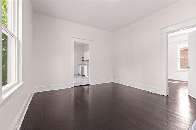 spare room with baseboards and dark wood finished floors