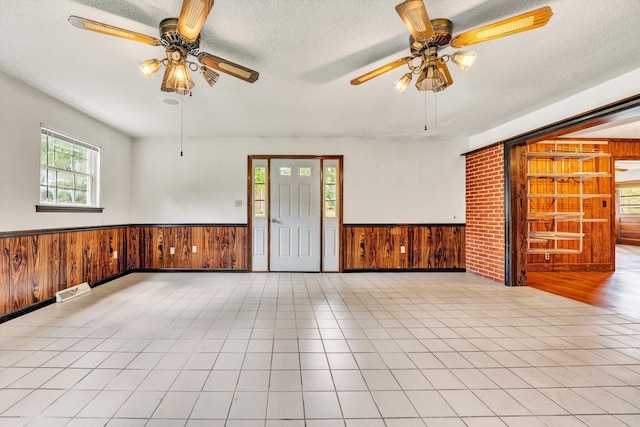7080 Oak Level Rd, Bassett, VA 24055 - spare room featuring ceiling fan, a wainscoted wall, wooden walls, and a healthy amount of sunlight
