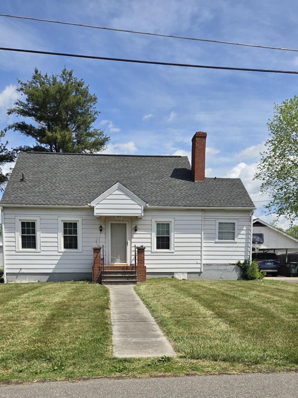 cape cod home featuring a chimney, roof with shingles, and a front lawn