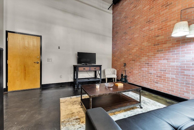 living room with brick wall, concrete floors, baseboards, and a towering ceiling