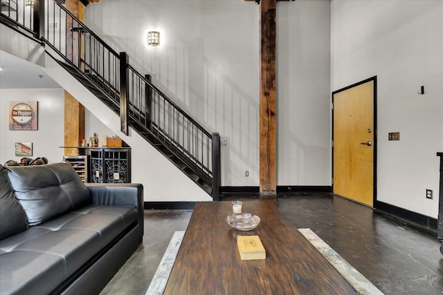 living room with a high ceiling, concrete floors, baseboards, and stairway