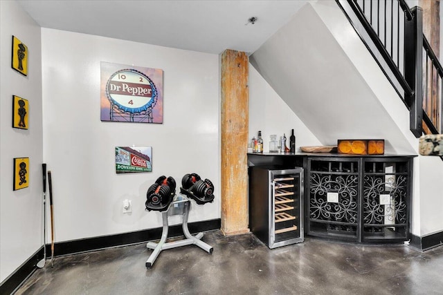 bar with concrete floors, baseboards, a dry bar, and wine cooler