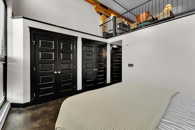 bedroom featuring baseboard heating, concrete floors, and a towering ceiling