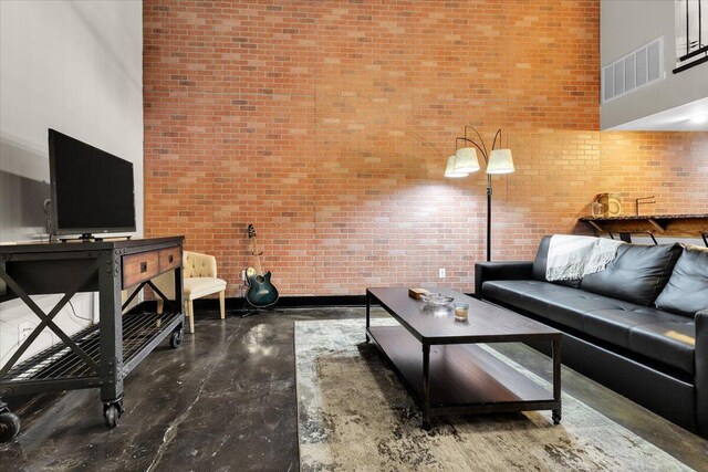 living area with a high ceiling, brick wall, and visible vents