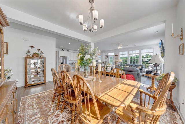 dining room with light wood-type flooring, baseboards, and ceiling fan with notable chandelier