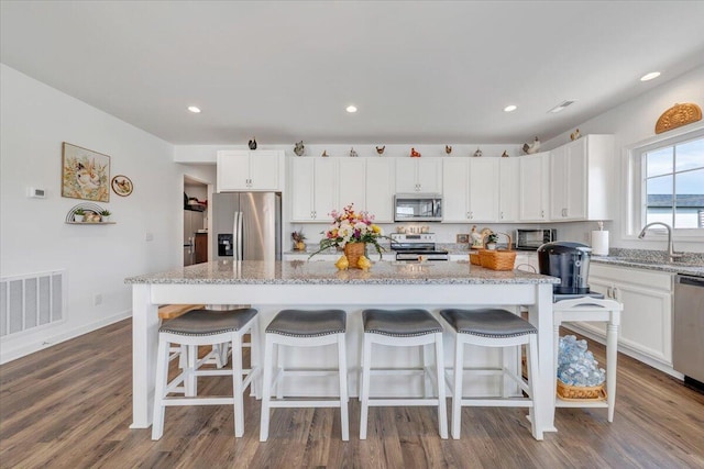 kitchen with visible vents, white cabinetry, a sink, dark wood finished floors, and stainless steel appliances