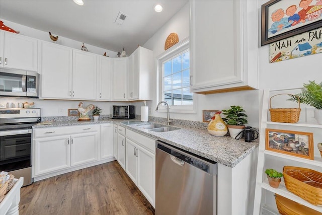 kitchen featuring a sink, appliances with stainless steel finishes, white cabinets, and visible vents